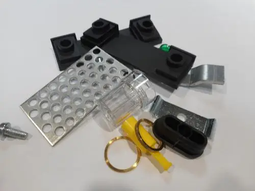 Verschiedene Komponenten und Materialien, darunter Metallbleche, Kunststoffteile, ein transparenter Behälter und ein kleiner Bolzen, die für Remeha Produkte verwendet werden können.